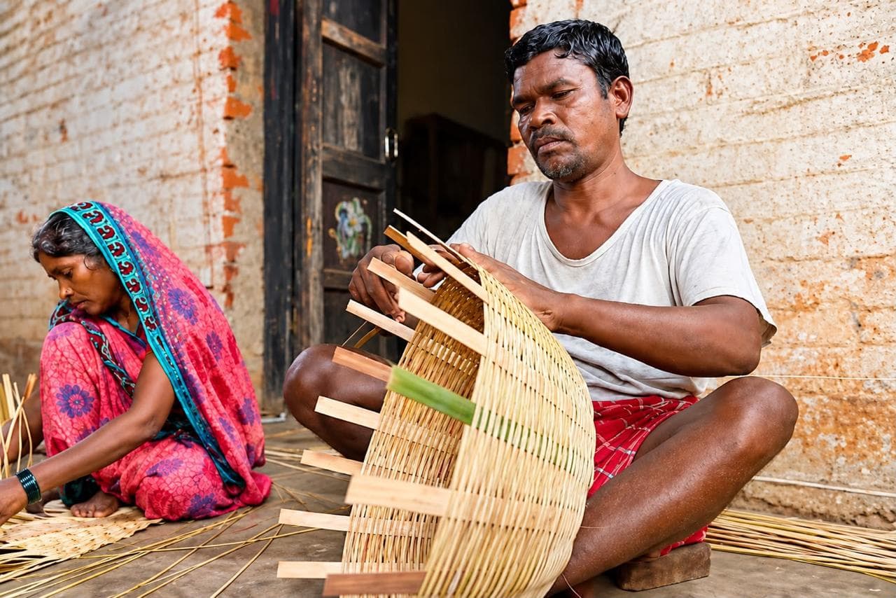 An artisan weaving a bamboo basket — self-reliant livelihoods.